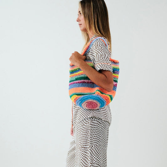 Woman holding a colorful striped tote bag against a white background