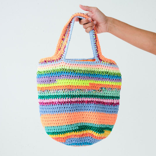 Multicolored striped crochet bag held by a hand against a white background