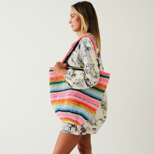 Woman holding a colorful striped bag against a white background