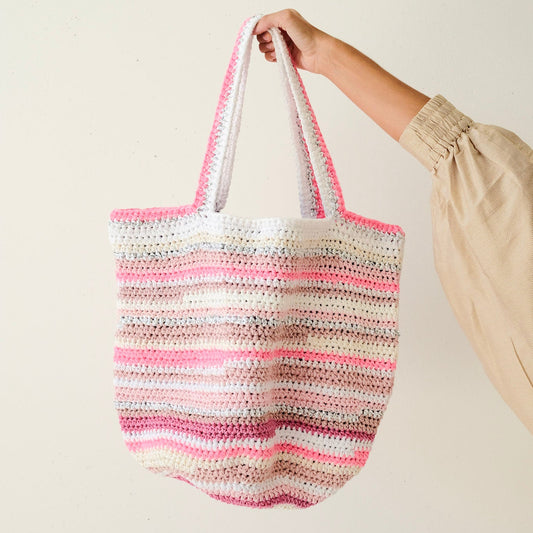Hand holding a striped crochet bag against a plain background