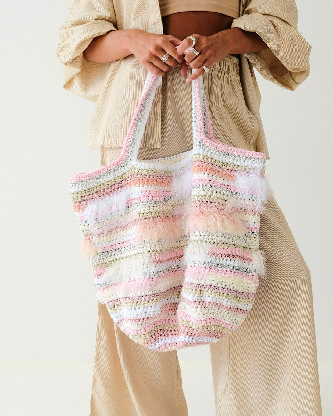 Person holding a striped woven bag against a plain background