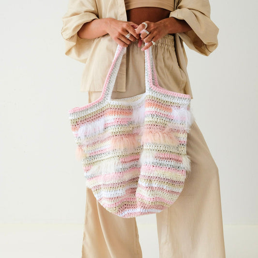 Person holding a striped woven bag against a plain background