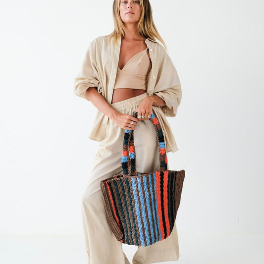 Woman holding a striped tote bag against a white background
