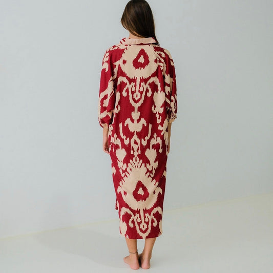 Woman wearing a red and beige patterned dress on a white background