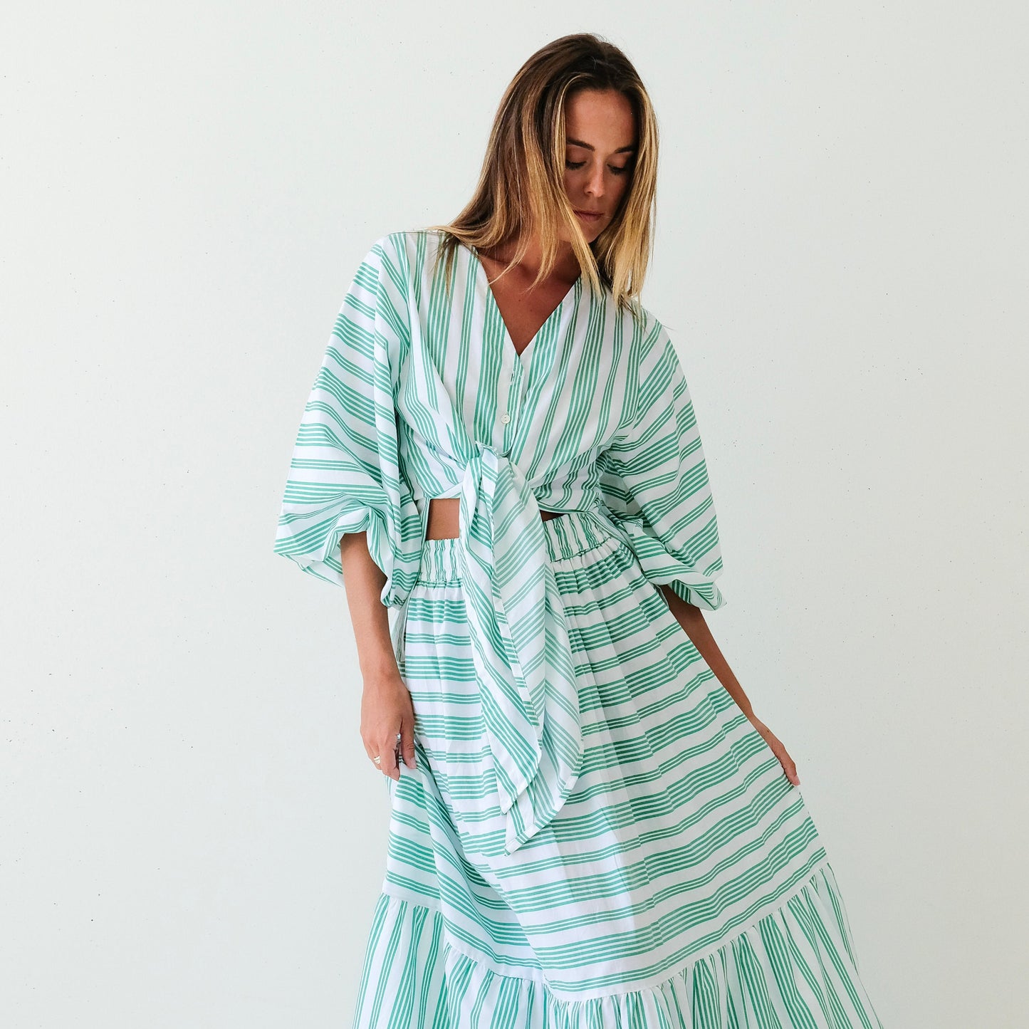 Woman wearing a green and white striped dress on a white background