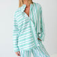 Woman wearing a green and white striped outfit against a plain background
