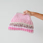 Hand holding a pink and brown gradient knitted bag against a light gray background