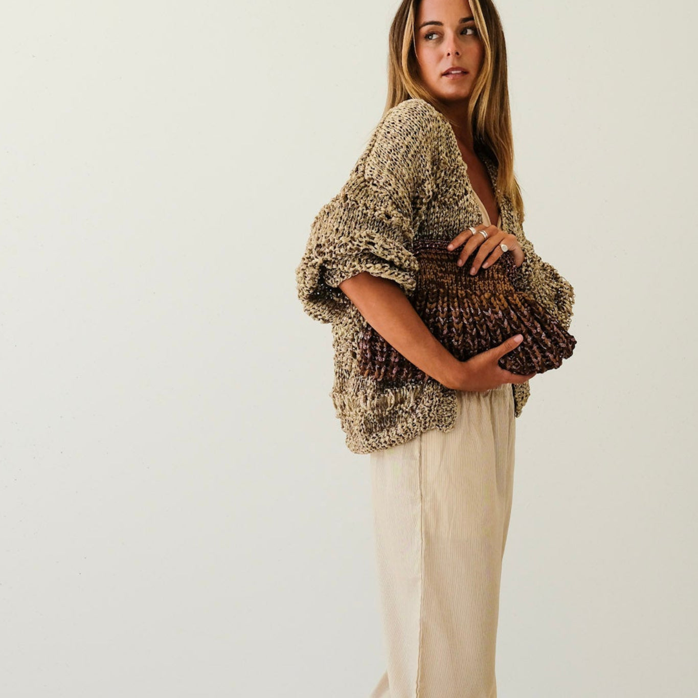 Woman wearing a textured shawl over a beige outfit on a white background