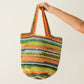 Colorful striped crochet bag held by a person against a plain background