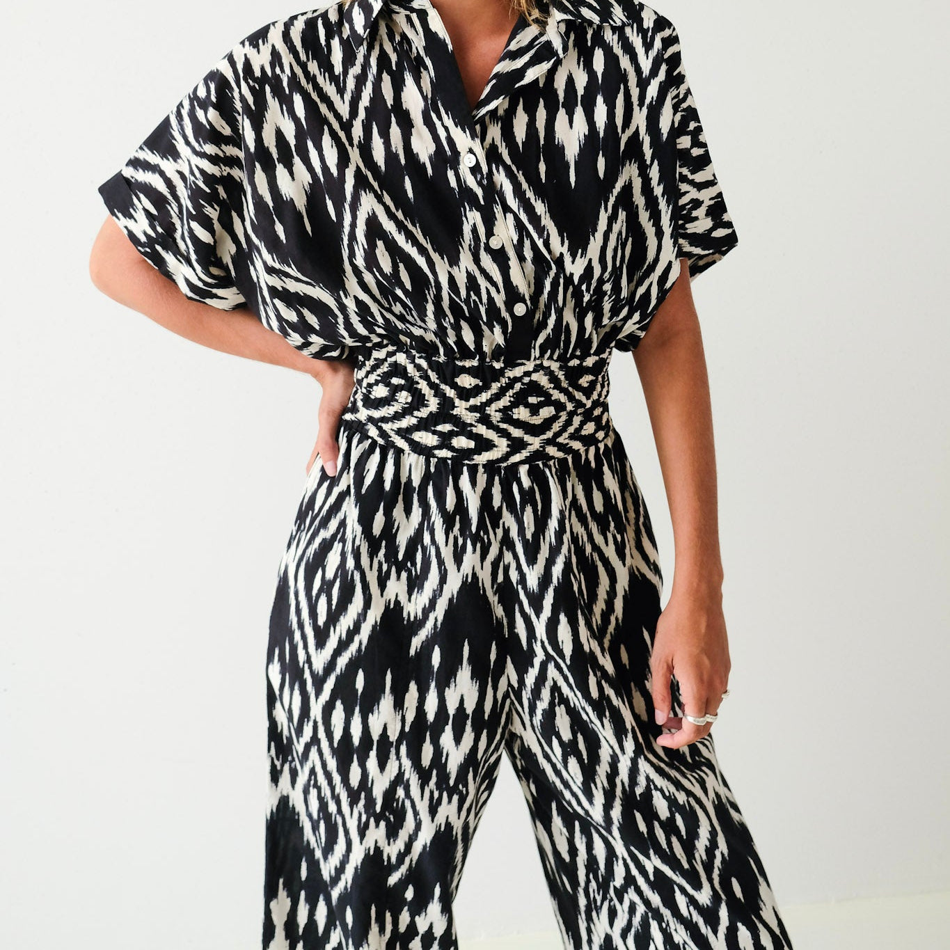 Woman wearing a black and white patterned outfit against a plain background