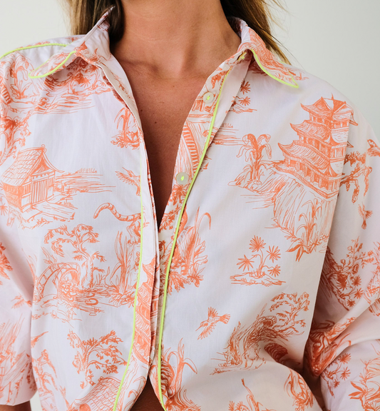 Close-up of a person wearing a patterned shirt with orange designs on a white background