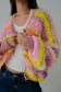 Person wearing a colorful knitted cardigan with a plain background