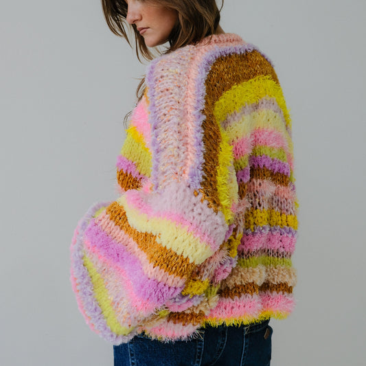 Woman wearing a colorful, patterned sweater against a plain background