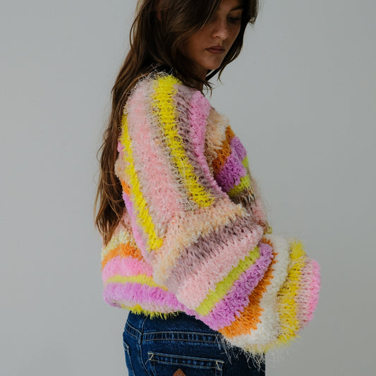 Person wearing a colorful, knitted sweater against a plain background