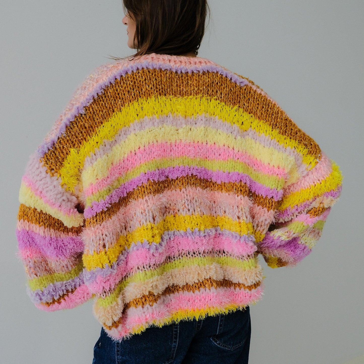 Person wearing a colorful, fluffy sweater against a plain background