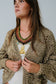 Woman wearing a patterned cardigan and colorful necklace against a plain background