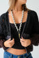 Person wearing a black textured cardigan over a black top with a white background
