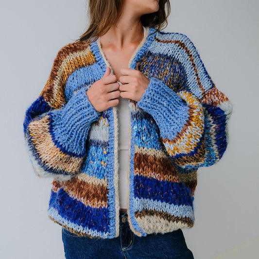Woman wearing a colorful knitted cardigan against a plain background