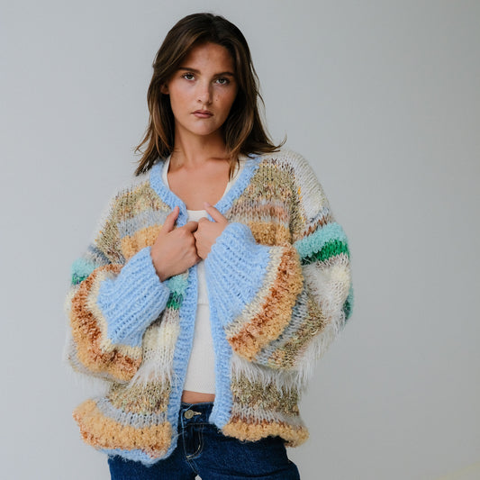 Woman wearing a colorful, patterned cardigan against a plain background