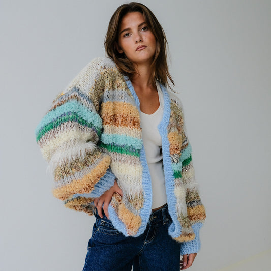 Woman wearing a colorful striped cardigan against a plain background