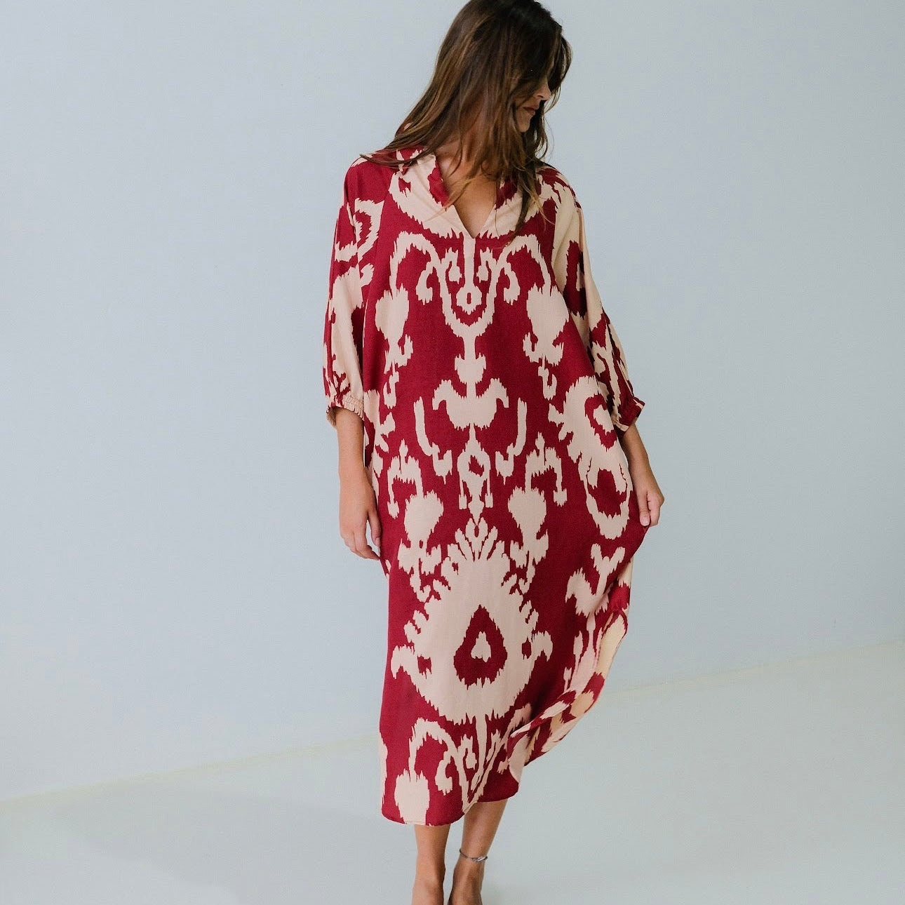 Woman wearing a red and white patterned dress against a plain background