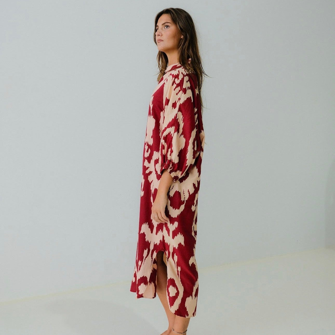 Woman wearing a red and white patterned dress on a plain background