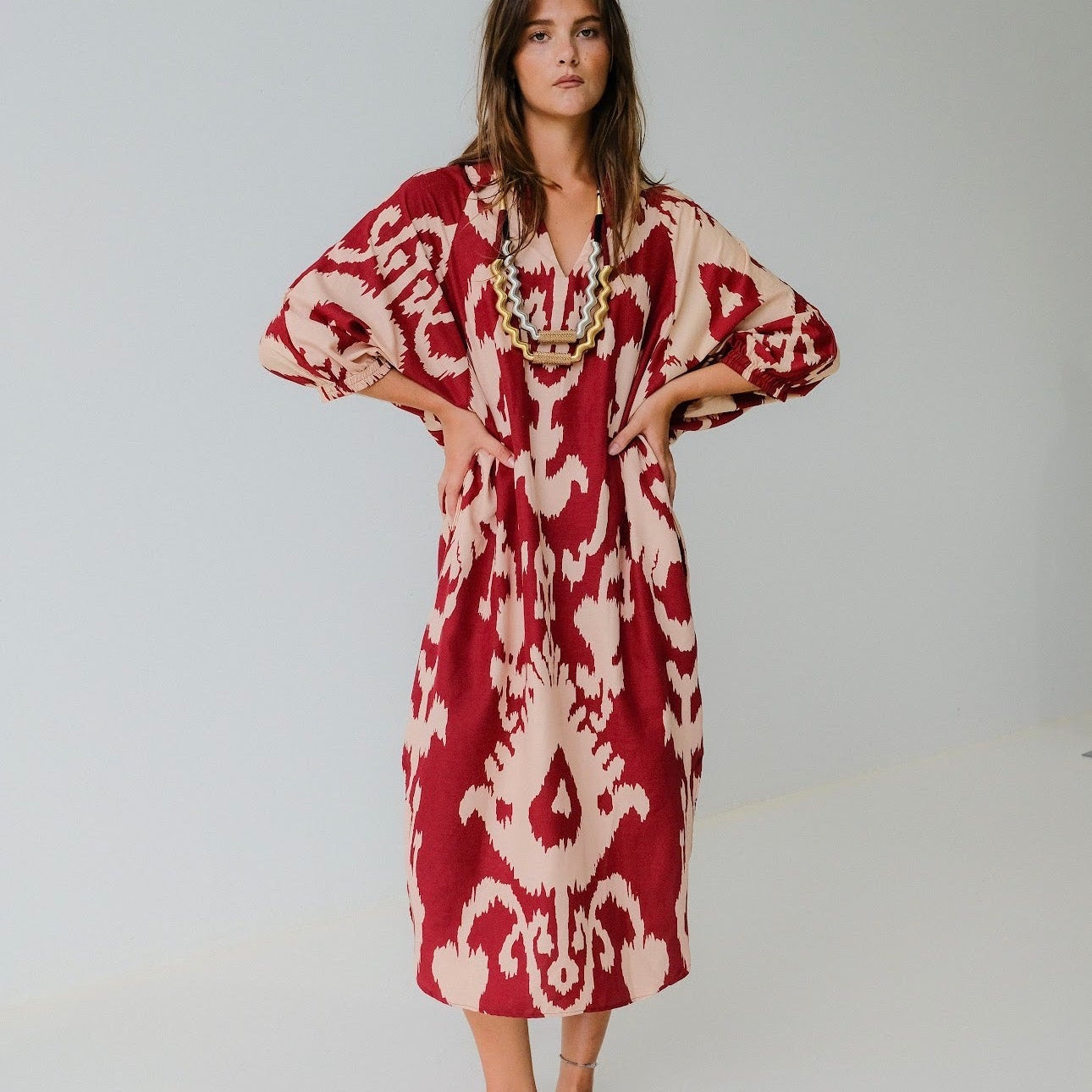 Woman wearing a red and white patterned dress on a plain background