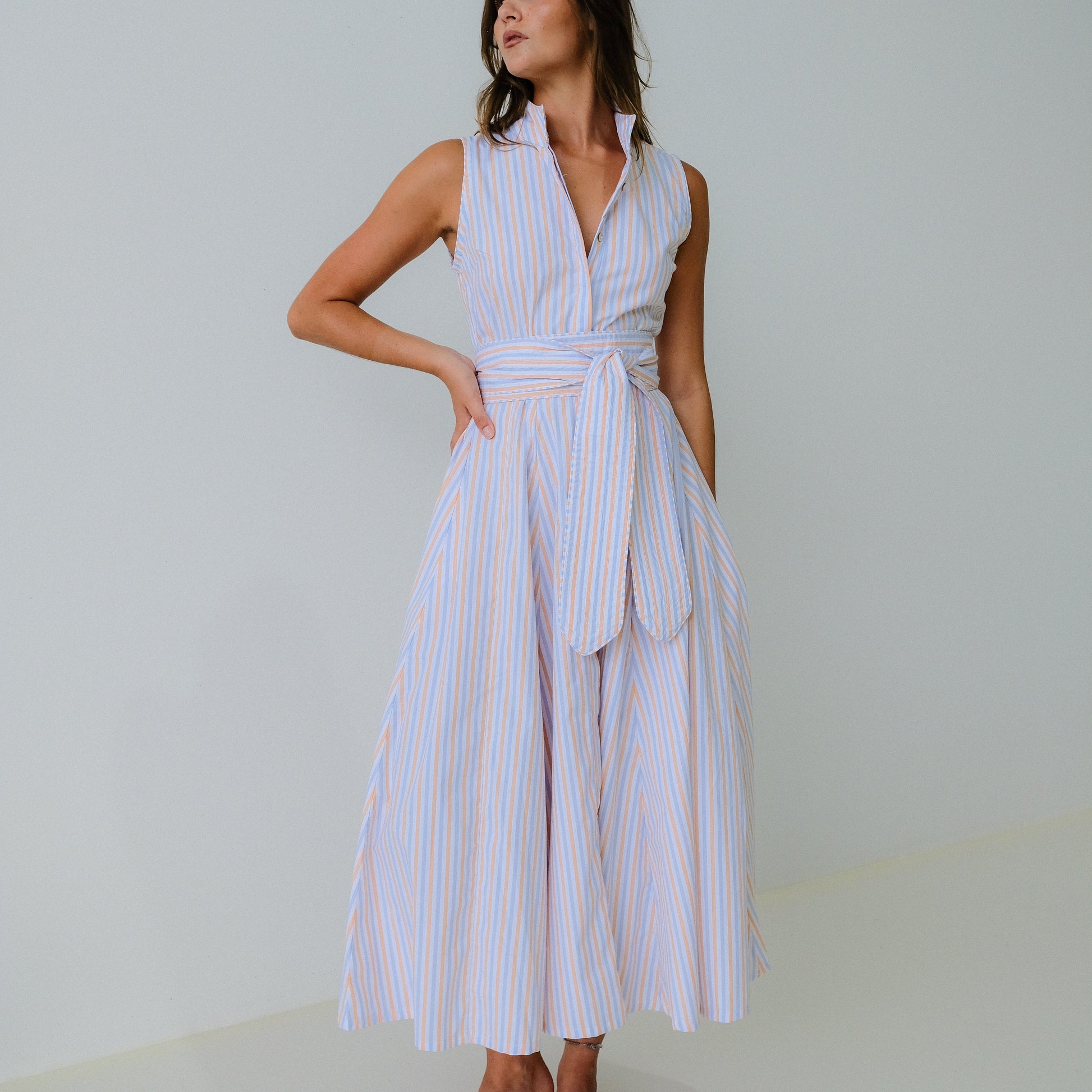 Woman wearing a white and blue striped dress against a plain background