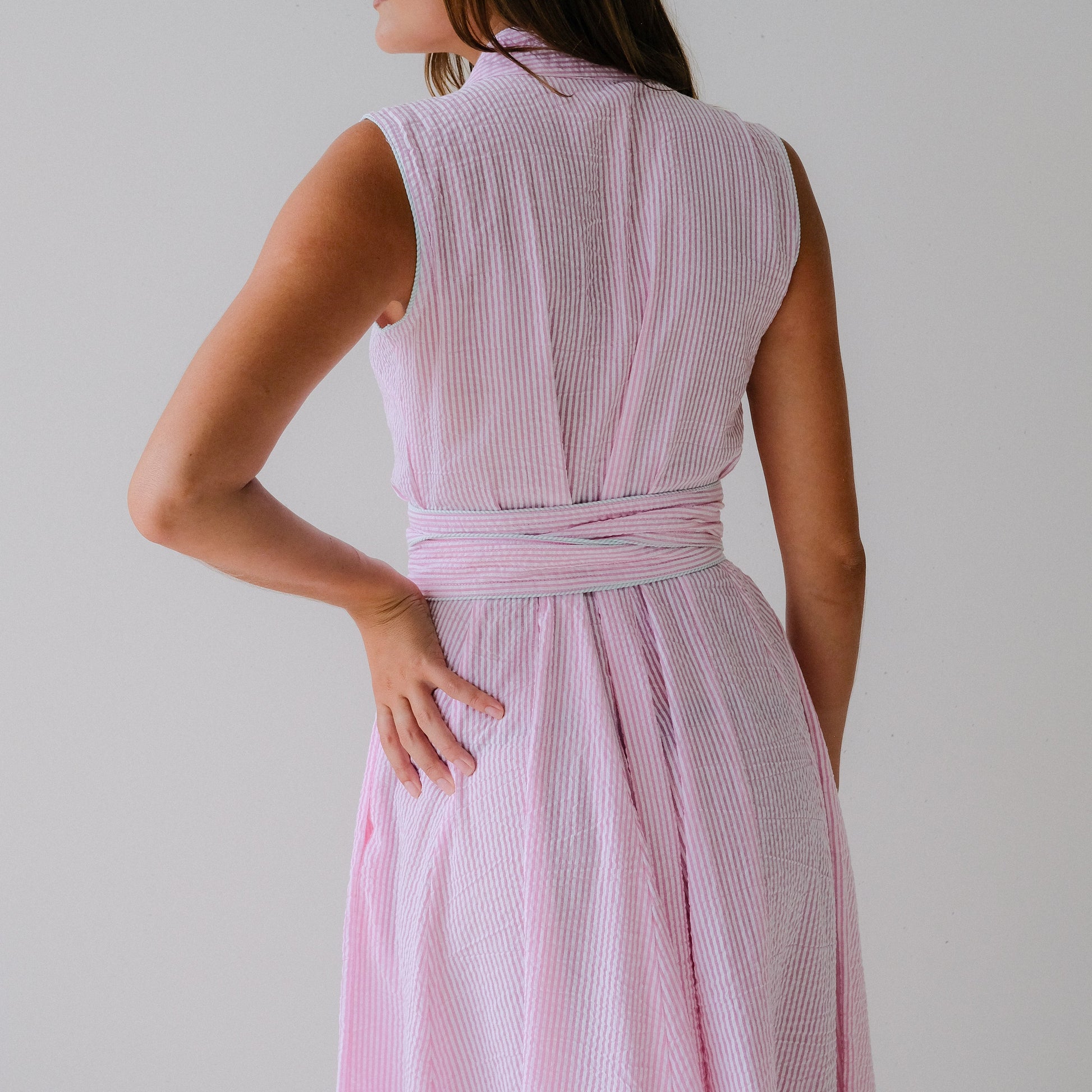Woman wearing a pink sleeveless dress against a plain background