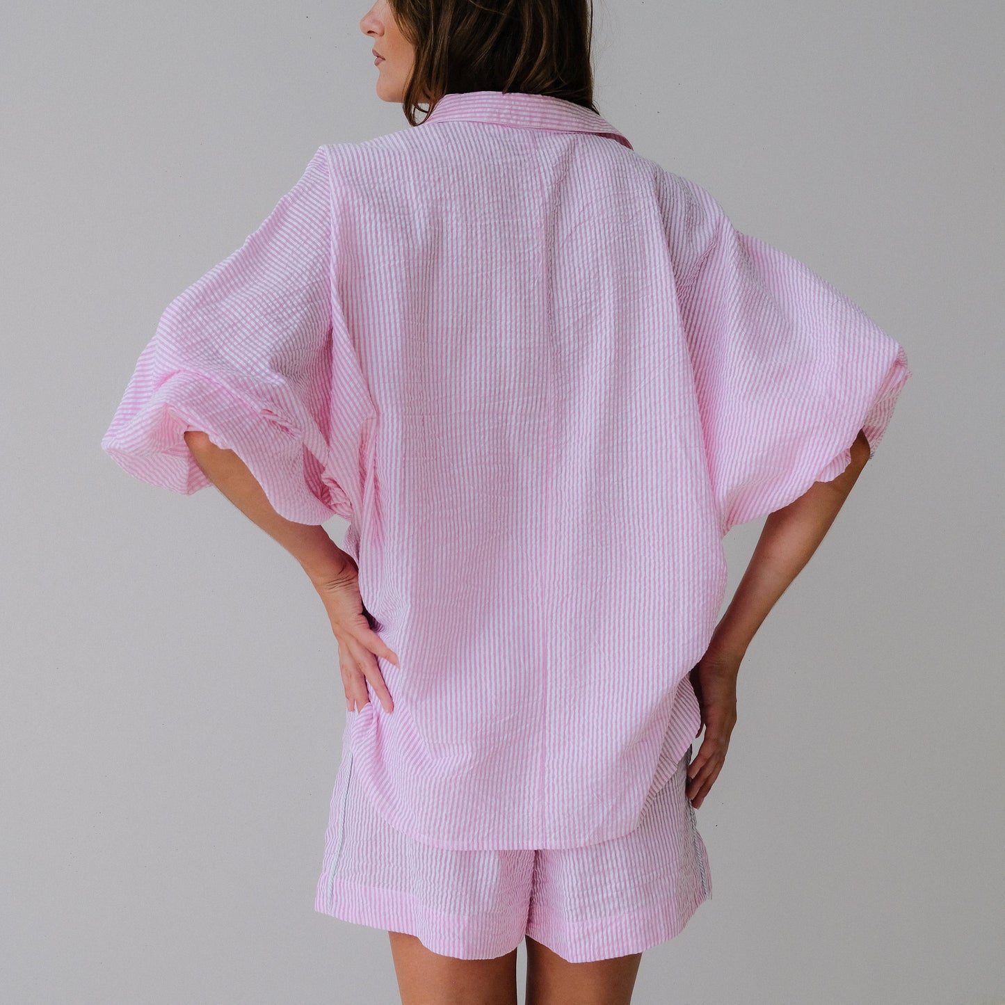 Person wearing a pink checkered kimono-style outfit on a plain background