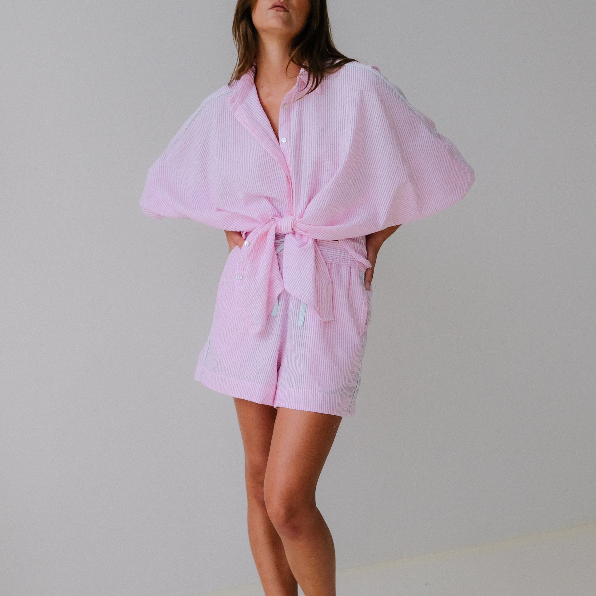 Woman wearing a pink robe against a plain background