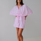 Woman wearing a pink robe against a plain background