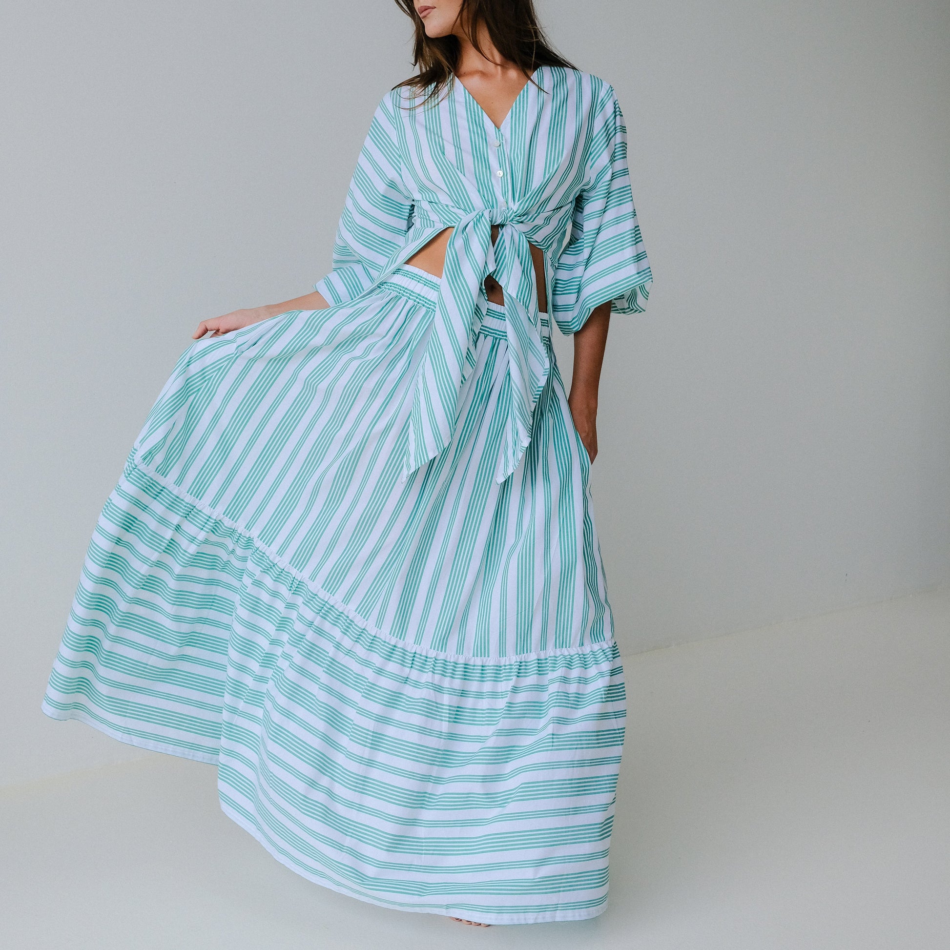 Woman wearing a light blue and white striped dress on a plain background