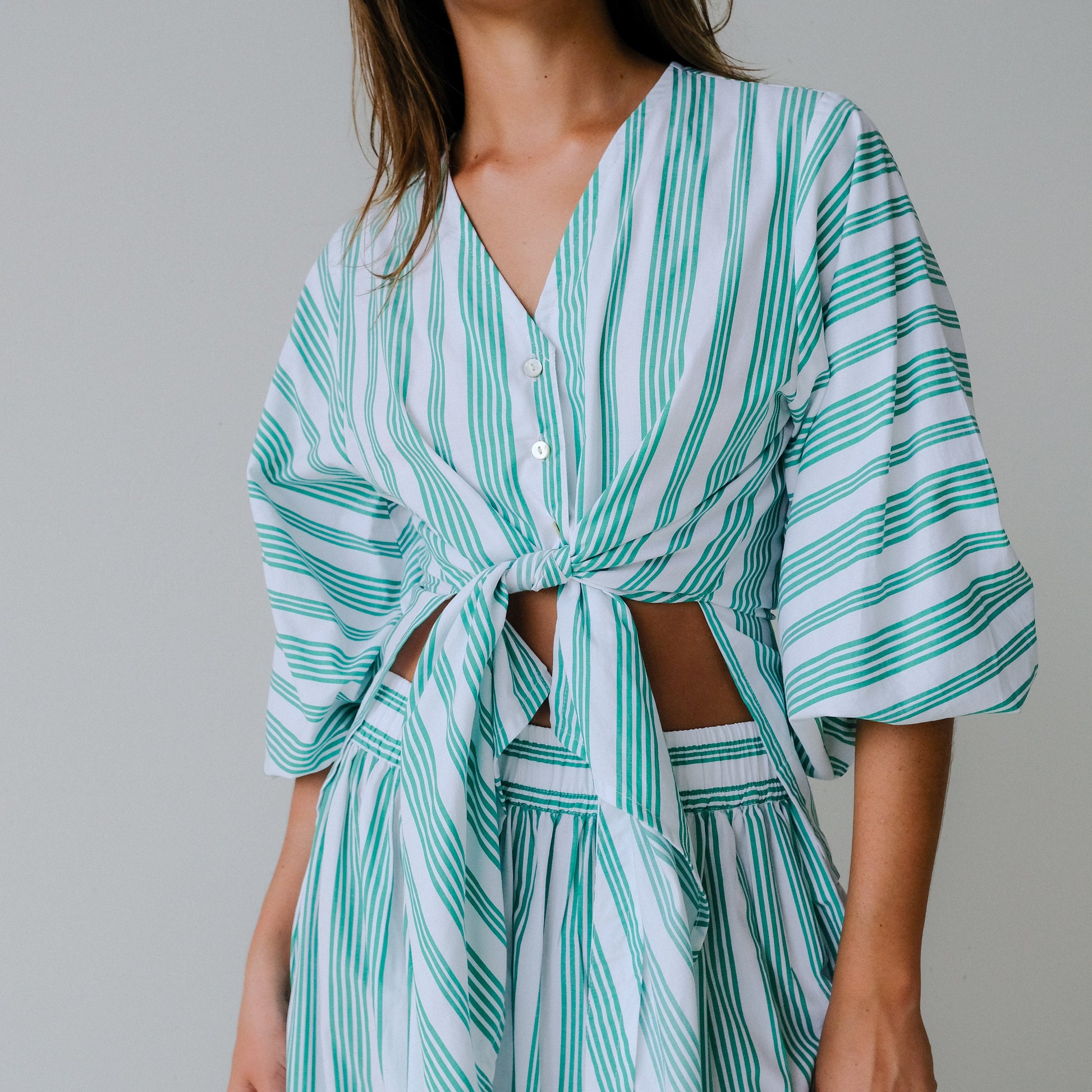 Woman wearing a green and white striped dress against a gray background