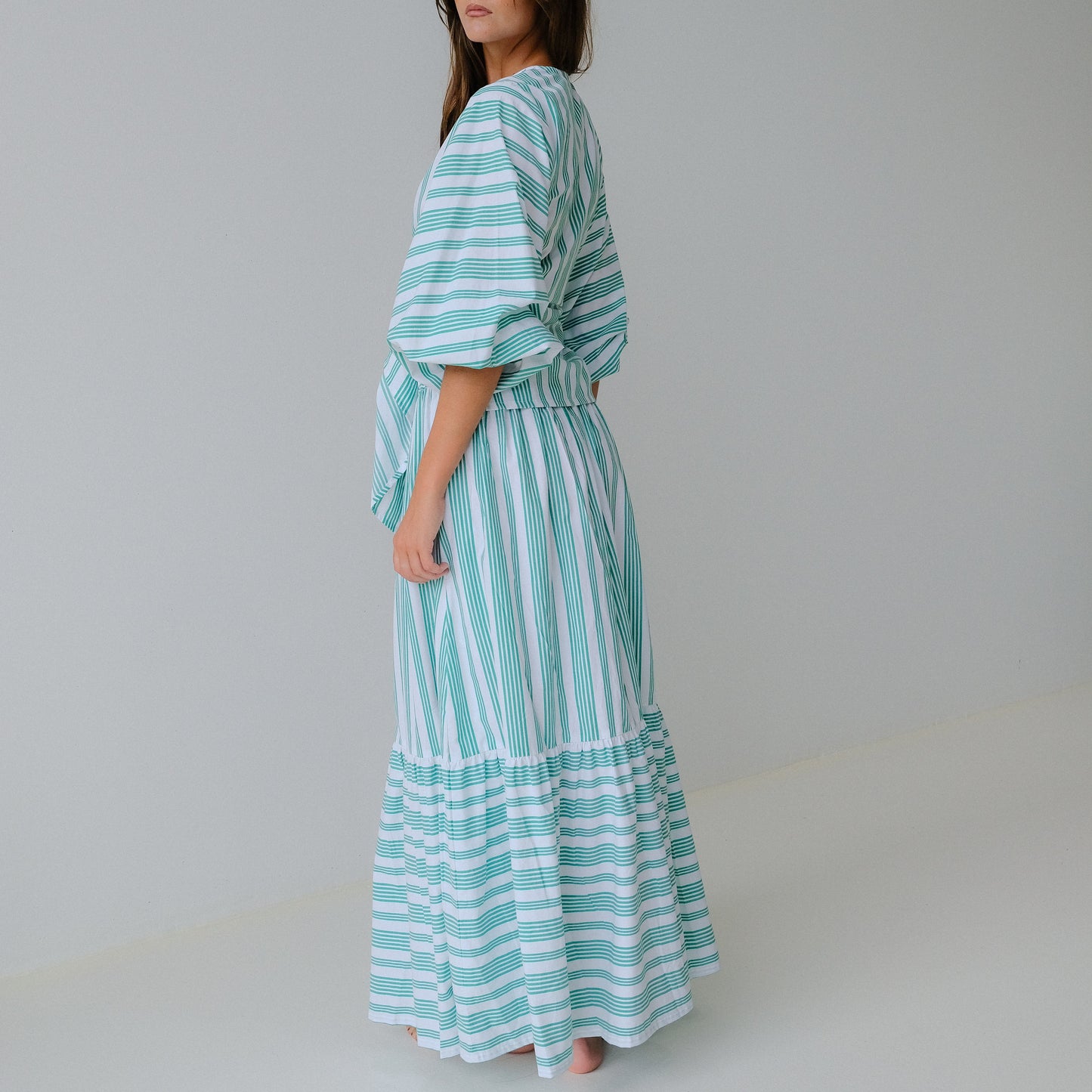 Woman wearing a green and white striped dress against a plain background