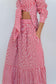 A red and white gingham two-piece set featuring a long-sleeve crop top with a side tie and a matching tiered maxi skirt with side pockets, shown on a model against a light gray background.