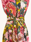 A close-up of a floral print dress with a matching tie belt, featuring a bold pattern of pink, red, yellow, and green flowers and leaves.