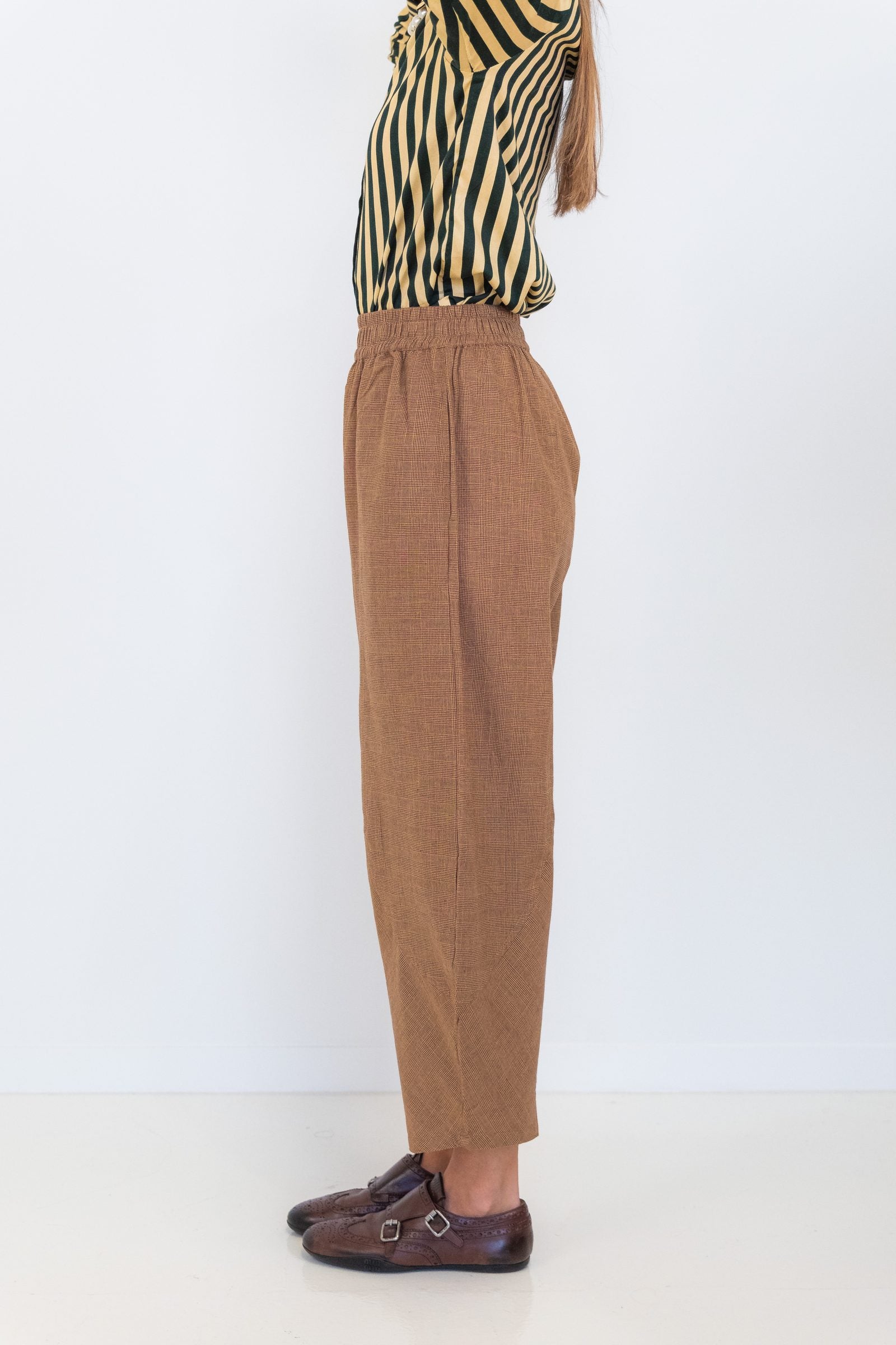 Side view of Chocolate Prince of Wales barrel pants showing the relaxed curved-leg silhouette.