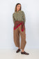Model wearing Chocolate Prince of Wales barrel pants with a striped shirt and red scarf tied at the waist.