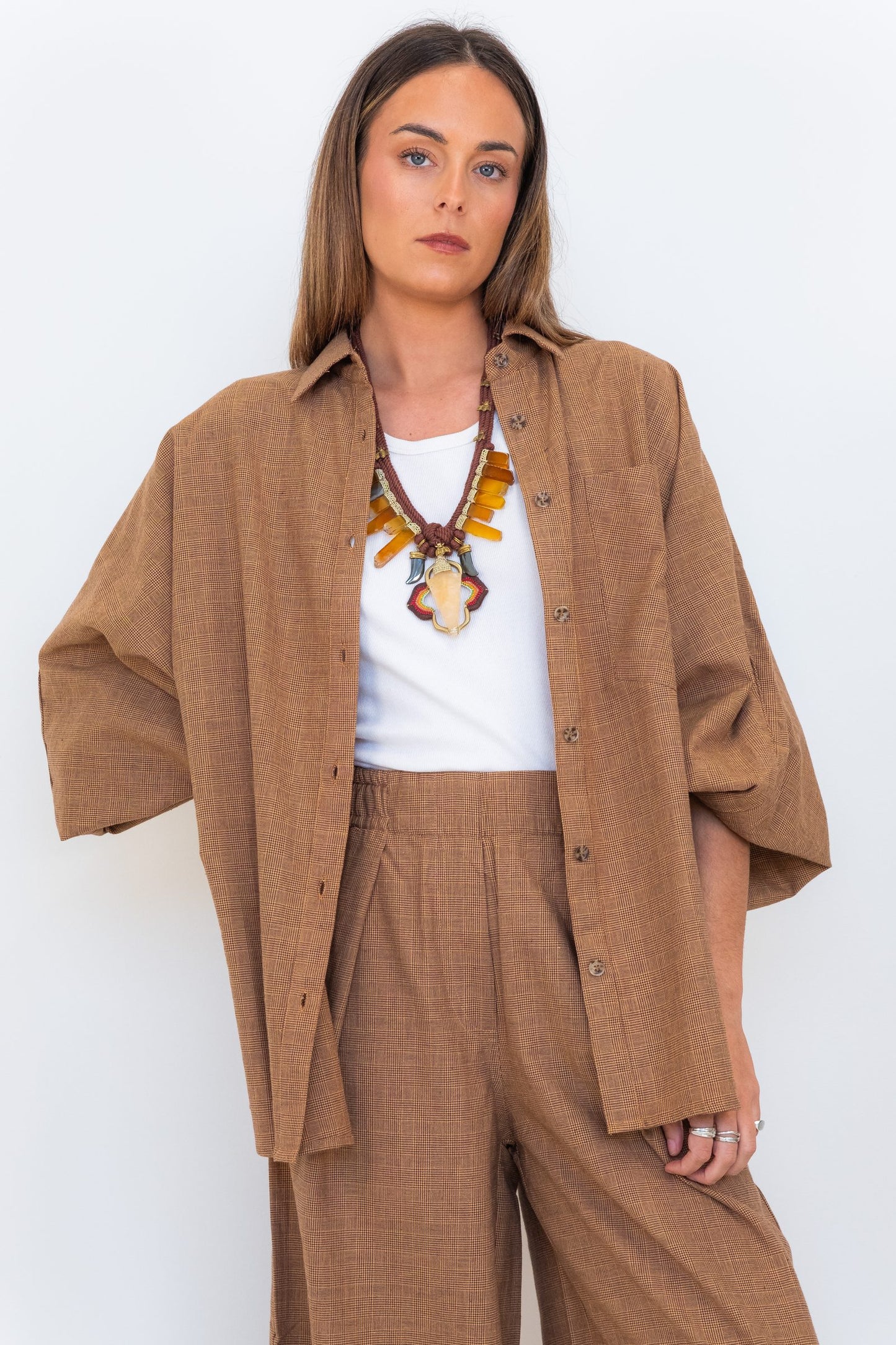 Model wearing the Chocolate Prince of Wales Butterfly Shirt open over a white tank with matching check trousers.