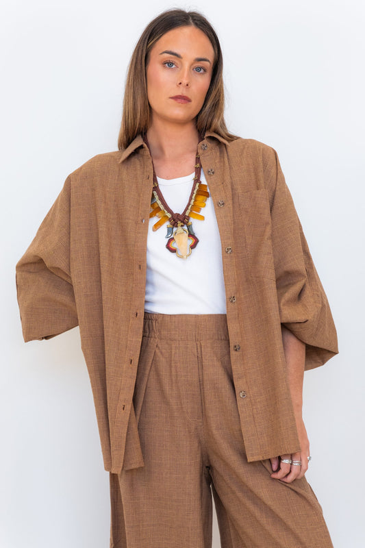 Model wearing the Chocolate Prince of Wales Butterfly Shirt open over a white tank with matching check trousers.