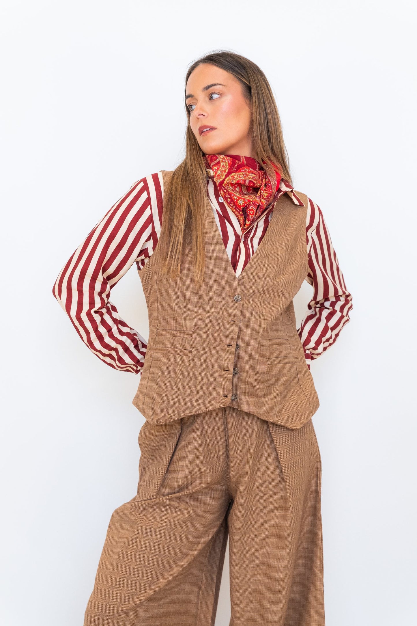 Model wearing the Chocolate Prince of Wales Vest over a red-and-white striped shirt with matching check trousers and a red scarf.