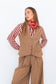 Model wearing the Chocolate Prince of Wales Vest over a red-and-white striped shirt with matching check trousers and a red scarf.