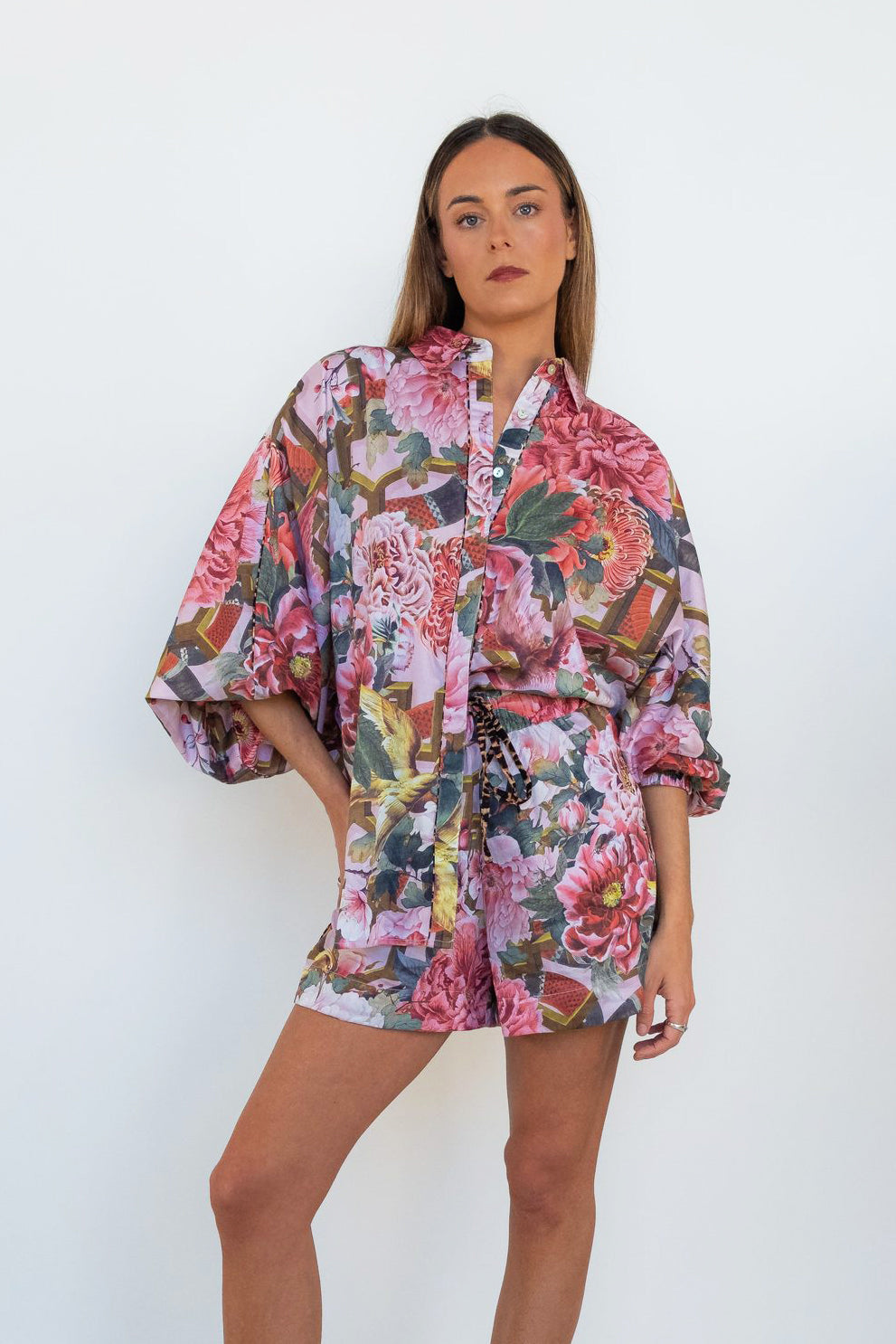 Front view of a model wearing the Ophelia Pink Butterfly Shirt with oversized butterfly sleeves and a pink floral print.