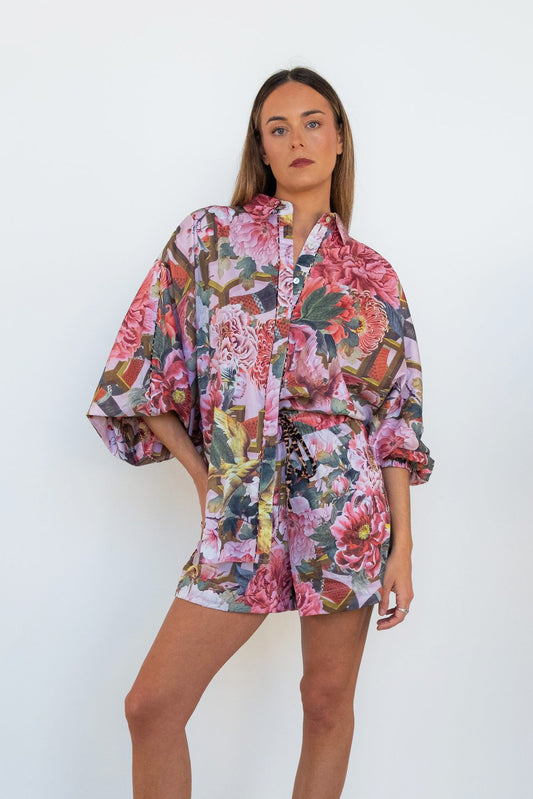 Front view of a model wearing the Ophelia Pink Butterfly Shirt with oversized butterfly sleeves and a pink floral print.