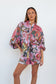 Front view of a model wearing the Ophelia Pink Butterfly Shirt with oversized butterfly sleeves and a pink floral print.