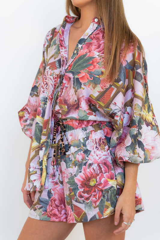Model wearing the Ophelia Pink Butterfly Shirt with matching pink floral shorts.