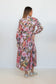 Back view of a model wearing the Ophelia pink floral-and-chain print drop-waist dress.