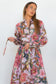 Model adjusting the slim tie belt on the Ophelia pink floral-and-chain print drop-waist dress.
