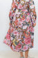 Rear three-quarter view of the pink floral-and-chain print dress, showing the slim waist tie.